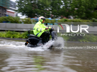 People are riding their bikes on a flooded road in Lianyun district, Lianyungang, China, on July 9, 2024. (