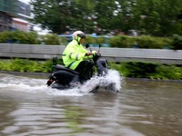 People are riding their bikes on a flooded road in Lianyun district, Lianyungang, China, on July 9, 2024. (