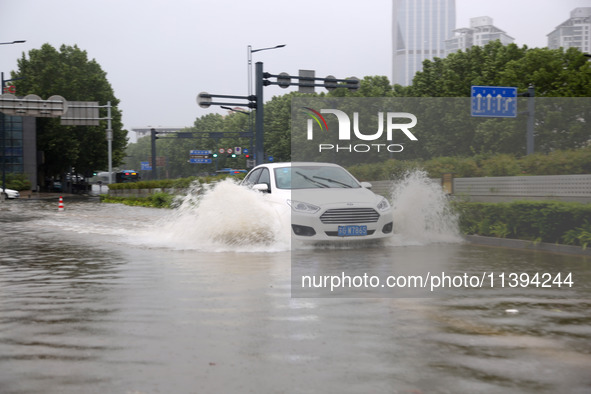 Vehicles are driving slowly through water on a road in Lianyun district, Lianyungang city, East China's Jiangsu province, on July 9, 2024. 