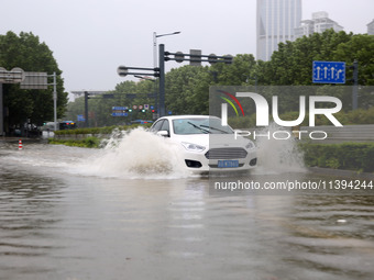 Vehicles are driving slowly through water on a road in Lianyun district, Lianyungang city, East China's Jiangsu province, on July 9, 2024. (