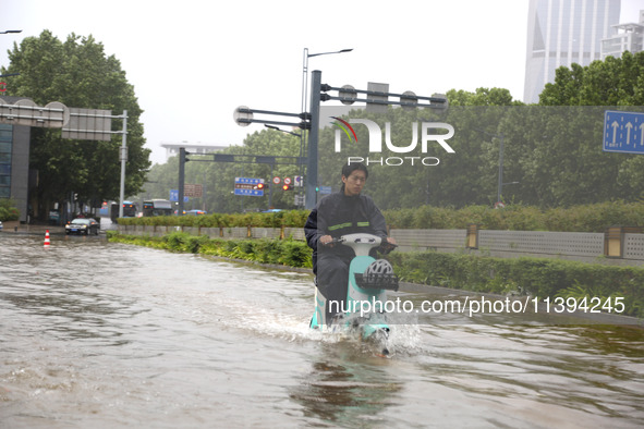 People are riding their bikes on a flooded road in Lianyun district, Lianyungang, China, on July 9, 2024. 