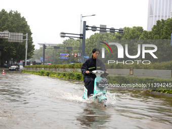 People are riding their bikes on a flooded road in Lianyun district, Lianyungang, China, on July 9, 2024. (