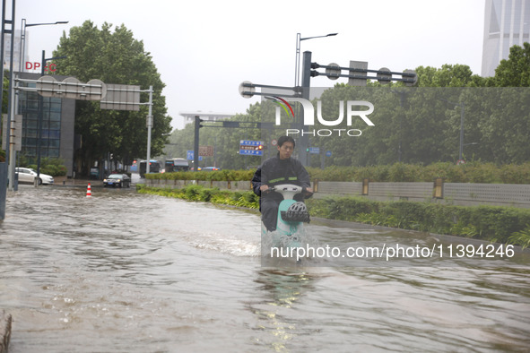 People are riding their bikes on a flooded road in Lianyun district, Lianyungang, China, on July 9, 2024. 