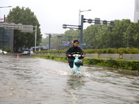 People are riding their bikes on a flooded road in Lianyun district, Lianyungang, China, on July 9, 2024. (