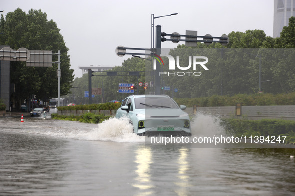 Vehicles are driving slowly through water on a road in Lianyun district, Lianyungang city, East China's Jiangsu province, on July 9, 2024. 