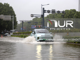 Vehicles are driving slowly through water on a road in Lianyun district, Lianyungang city, East China's Jiangsu province, on July 9, 2024. (