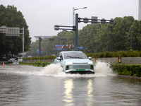 Vehicles are driving slowly through water on a road in Lianyun district, Lianyungang city, East China's Jiangsu province, on July 9, 2024. (