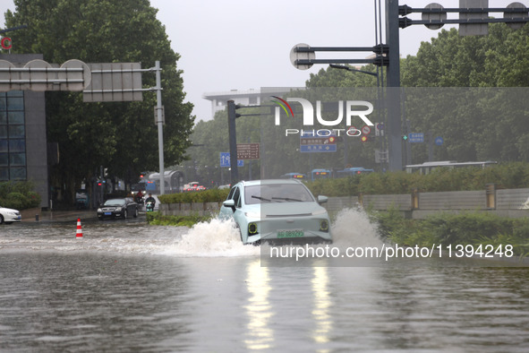 Vehicles are driving slowly through water on a road in Lianyun district, Lianyungang city, East China's Jiangsu province, on July 9, 2024. 