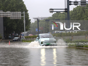 Vehicles are driving slowly through water on a road in Lianyun district, Lianyungang city, East China's Jiangsu province, on July 9, 2024. (