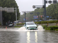 Vehicles are driving slowly through water on a road in Lianyun district, Lianyungang city, East China's Jiangsu province, on July 9, 2024. (