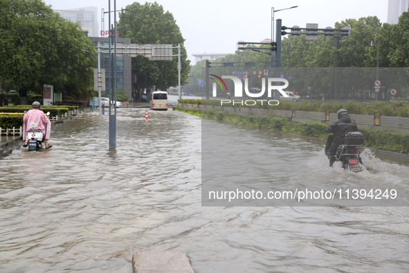 People are riding their bikes on a flooded road in Lianyun district, Lianyungang, China, on July 9, 2024. 