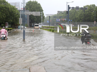 People are riding their bikes on a flooded road in Lianyun district, Lianyungang, China, on July 9, 2024. (