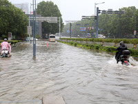 People are riding their bikes on a flooded road in Lianyun district, Lianyungang, China, on July 9, 2024. (