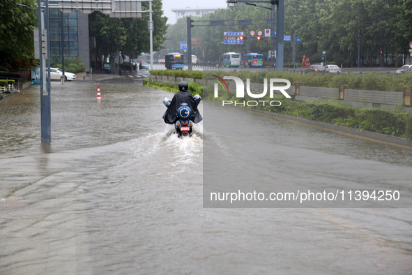 People are riding their bikes on a flooded road in Lianyun district, Lianyungang, China, on July 9, 2024. 