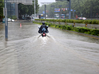 People are riding their bikes on a flooded road in Lianyun district, Lianyungang, China, on July 9, 2024. (