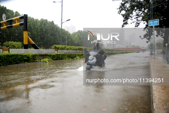 People are riding their bikes on a flooded road in Lianyun district, Lianyungang, China, on July 9, 2024. 