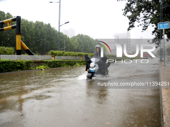 People are riding their bikes on a flooded road in Lianyun district, Lianyungang, China, on July 9, 2024. (