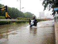 People are riding their bikes on a flooded road in Lianyun district, Lianyungang, China, on July 9, 2024. (