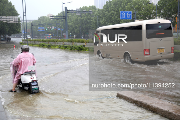 People are riding their bikes on a flooded road in Lianyun district, Lianyungang, China, on July 9, 2024. 