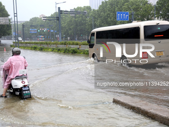 People are riding their bikes on a flooded road in Lianyun district, Lianyungang, China, on July 9, 2024. (