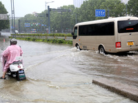 People are riding their bikes on a flooded road in Lianyun district, Lianyungang, China, on July 9, 2024. (