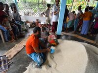 Flood-affected people are receiving food supplies at a relief center during flooding in a low-lying area in Nagaon District of Assam, India,...