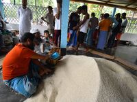 Flood-affected people are receiving food supplies at a relief center during flooding in a low-lying area in Nagaon District of Assam, India,...