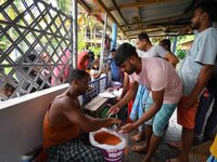 Flood-affected people are receiving food supplies at a relief center during flooding in a low-lying area in Nagaon District of Assam, India,...