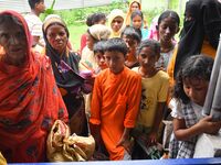 Flood-affected people are waiting in line to receive food supplies at a relief center during flooding in a low-lying area in Nagaon District...