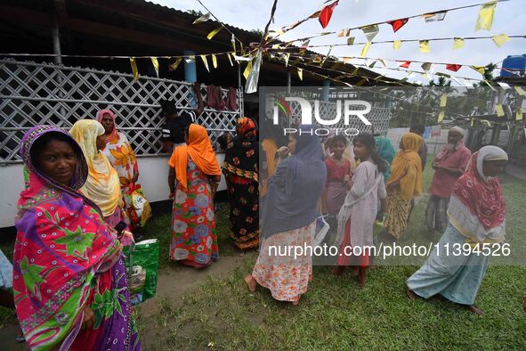 Flood-affected people are waiting in line to receive food supplies at a relief center during flooding in a low-lying area in Nagaon District...