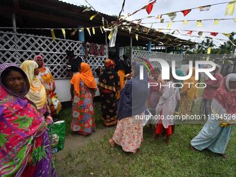 Flood-affected people are waiting in line to receive food supplies at a relief center during flooding in a low-lying area in Nagaon District...