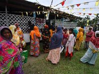 Flood-affected people are waiting in line to receive food supplies at a relief center during flooding in a low-lying area in Nagaon District...