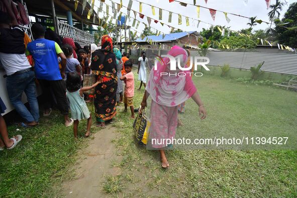 Flood-affected people are gathering to receive food supplies at a relief center during flooding in a low-lying area in Nagaon District of As...