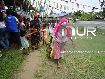 Flood-affected people are gathering to receive food supplies at a relief center during flooding in a low-lying area in Nagaon District of As...