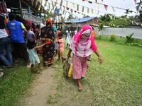 Flood-affected people are gathering to receive food supplies at a relief center during flooding in a low-lying area in Nagaon District of As...