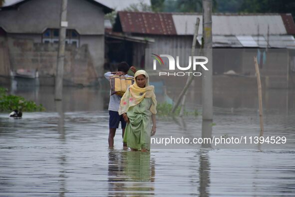 People are moving through a flooded road after heavy rainfall in Nagaon district of Assam, India, on July 9, 2024. 