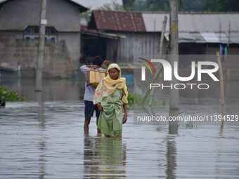 People are moving through a flooded road after heavy rainfall in Nagaon district of Assam, India, on July 9, 2024. (