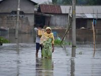 People are moving through a flooded road after heavy rainfall in Nagaon district of Assam, India, on July 9, 2024. (