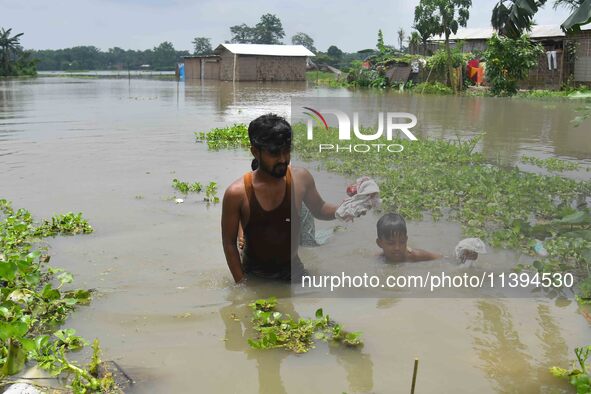 People are moving through a flooded area after heavy rainfall in Nagaon district of Assam, India, on July 9, 2024. 