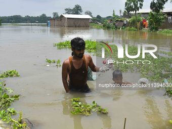 People are moving through a flooded area after heavy rainfall in Nagaon district of Assam, India, on July 9, 2024. (