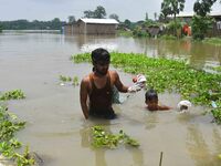 People are moving through a flooded area after heavy rainfall in Nagaon district of Assam, India, on July 9, 2024. (