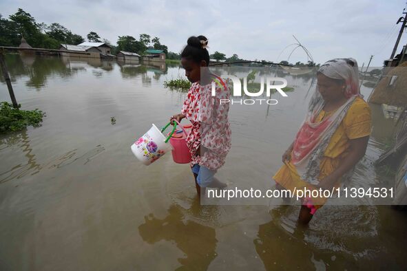 People are moving through a flooded road after heavy rainfall in Nagaon district of Assam, India, on July 9, 2024. 