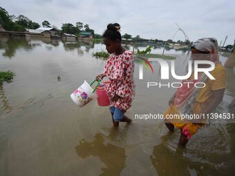 People are moving through a flooded road after heavy rainfall in Nagaon district of Assam, India, on July 9, 2024. (