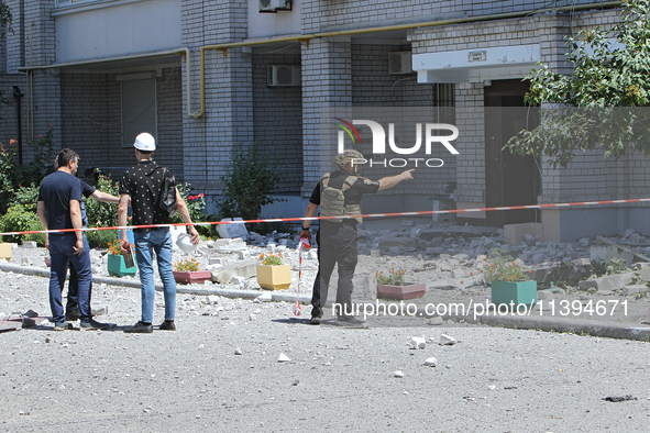 Men are staying behind a caution tape sealing off an apartment block damaged by the Russian missile attack in Dnipro, Ukraine, on July 8, 20...