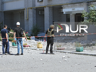 Men are staying behind a caution tape sealing off an apartment block damaged by the Russian missile attack in Dnipro, Ukraine, on July 8, 20...