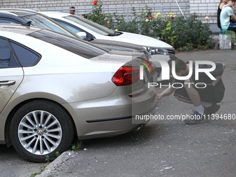 A young man is examining a car outside an apartment block damaged by the Russian missile attack in Dnipro, Ukraine, on July 8, 2024. NO USE...