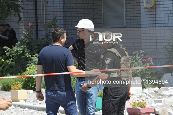 Men are staying behind a caution tape sealing off an apartment block damaged by the Russian missile attack in Dnipro, Ukraine, on July 8, 20...