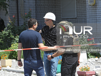 Men are staying behind a caution tape sealing off an apartment block damaged by the Russian missile attack in Dnipro, Ukraine, on July 8, 20...