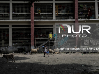 A boy is walking past a temporary flood shelter center to collect fresh drinking water in Jamalpur, Bangladesh, on July 09, 2024. (