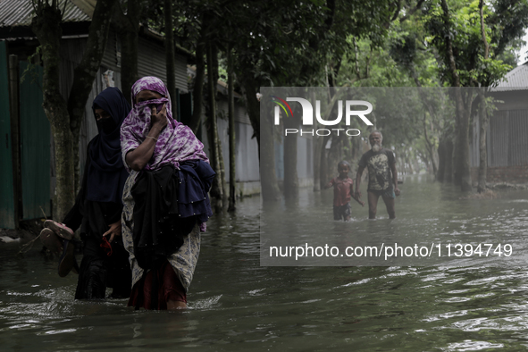 Women are walking past a street submerged by flood water in Jamalpur, Bangladesh, on July 9, 2024. 